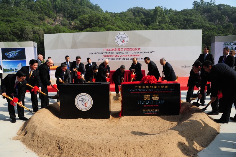 Shimon Peres, 92-year-old former Prime Minister of Israel, left of center space between cornerstones, and 87-year-old Li Ka Shing, right of center space between cornerstones, and a number of Chinese officials and Israeli administrators symbolically shovel dirt at the Guangdong-Technion construction site to launch the project.